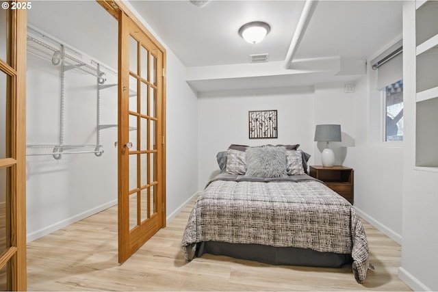 bedroom with baseboards, wood finished floors, and visible vents