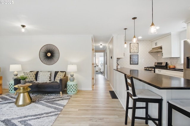 living room with light wood-style flooring, visible vents, crown molding, and baseboards