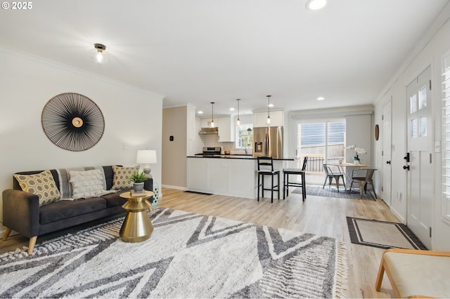 living area featuring recessed lighting, light wood-type flooring, baseboards, and ornamental molding