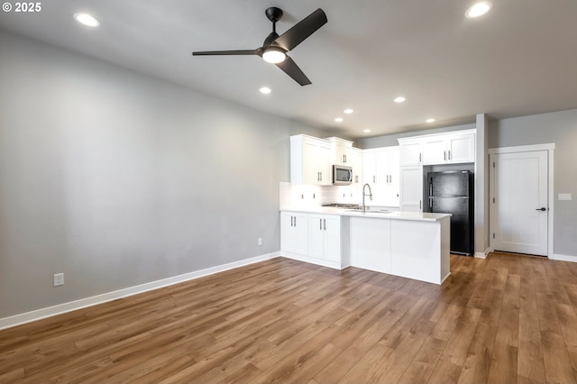 4111 SE Century Blvd, Hillsboro, OR 97123 - kitchen featuring freestanding refrigerator, stainless steel microwave, a peninsula, wood finished floors, and a ceiling fan