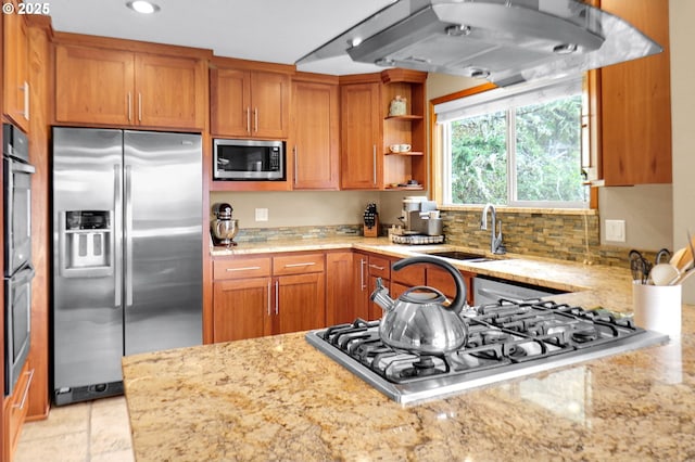 kitchen featuring appliances with stainless steel finishes, a sink, brown cabinetry, light stone countertops, and recessed lighting