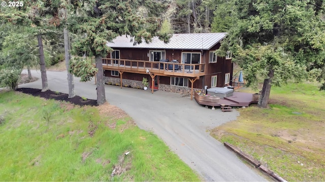 chalet / cabin featuring a wooden deck, metal roof, driveway, and a standing seam roof