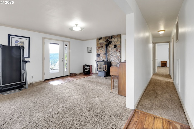 carpeted entryway featuring a wood stove and baseboards