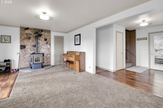 living room featuring a wood stove, baseboards, stairs, and wood-type flooring