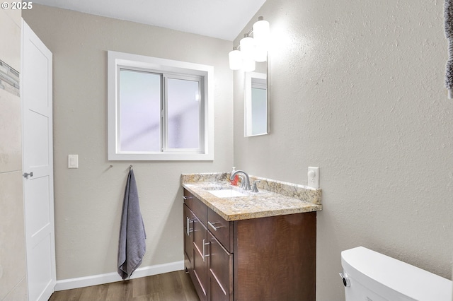 bathroom with wood finished floors, vanity, toilet, and baseboards