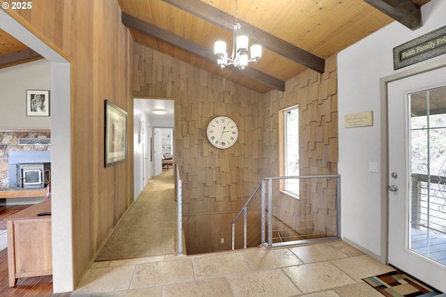 foyer entrance featuring stone tile floors, a chandelier, wooden ceiling, and baseboards