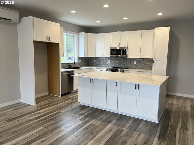 1028 Forest Heights St, Sutherlin, OR 97479 - kitchen featuring appliances with stainless steel finishes, an AC wall unit, a center island, white cabinetry, and backsplash