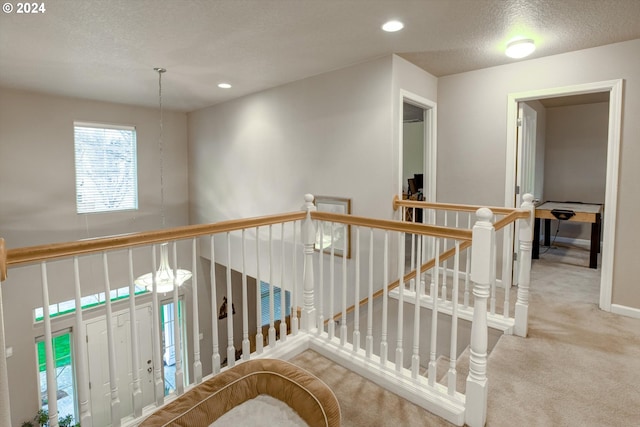 hall featuring a textured ceiling and carpet flooring