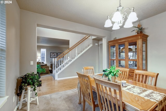 dining room with an inviting chandelier, light carpet, and a textured ceiling