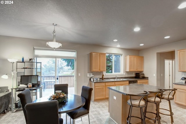 kitchen with dishwasher, pendant lighting, a center island, and light brown cabinets