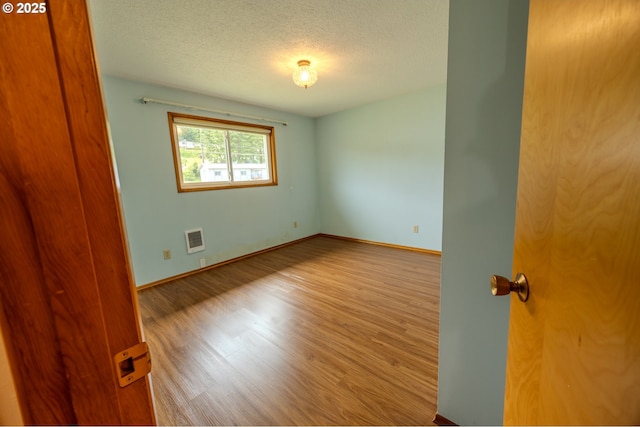 745 N 8th St, Lakeside, OR 97449 - empty room with wood finished floors, a textured ceiling, and baseboards