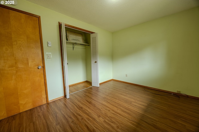 745 N 8th St, Lakeside, OR 97449 - unfurnished bedroom with wood finished floors, baseboards, a closet, and a textured ceiling