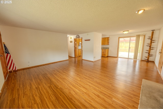 745 N 8th St, Lakeside, OR 97449 - unfurnished living room with a textured ceiling, light wood-type flooring, and baseboards