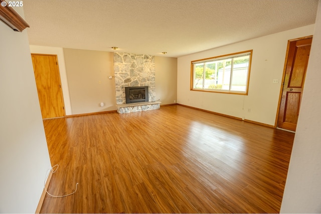 745 N 8th St, Lakeside, OR 97449 - unfurnished living room with wood finished floors, a fireplace, a textured ceiling, and baseboards