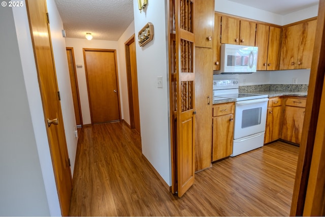 745 N 8th St, Lakeside, OR 97449 - kitchen with white appliances, wood finished floors, brown cabinetry, a textured ceiling, and light countertops