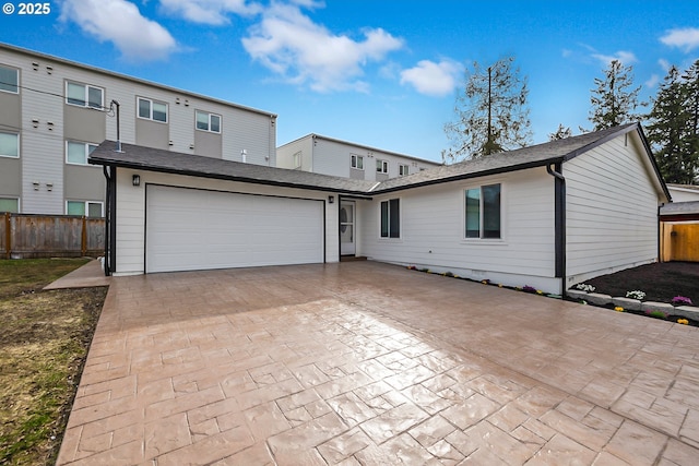 view of front facade with decorative driveway, fence, a garage, and roof with shingles