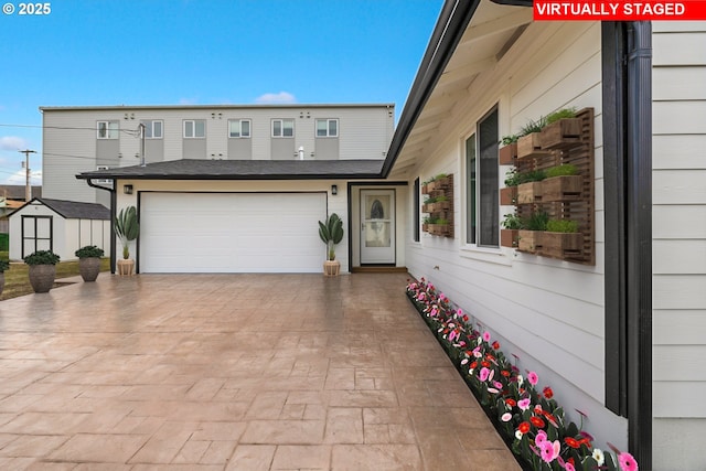 exterior space featuring driveway, a storage unit, and an attached garage