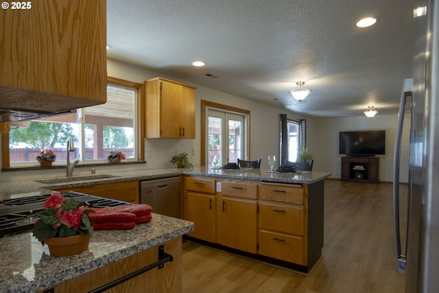 14604 NW 7th Pl, Vancouver, WA 98685 - kitchen with a peninsula, appliances with stainless steel finishes, a textured ceiling, open floor plan, and light wood-type flooring