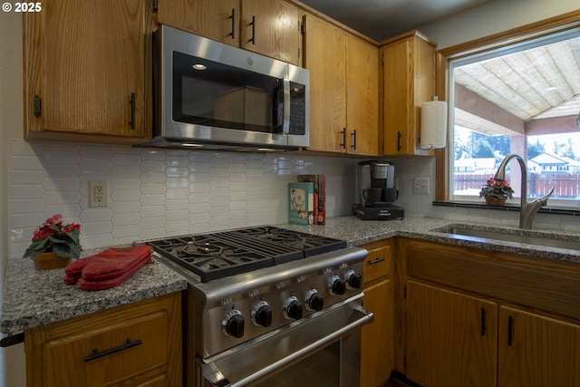 14604 NW 7th Pl, Vancouver, WA 98685 - kitchen featuring appliances with stainless steel finishes, tasteful backsplash, brown cabinets, lofted ceiling, and light stone countertops