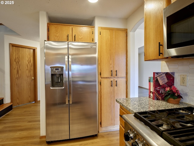 14604 NW 7th Pl, Vancouver, WA 98685 - kitchen with appliances with stainless steel finishes, backsplash, light wood finished floors, arched walkways, and light stone counters