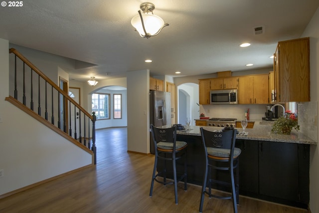 14604 NW 7th Pl, Vancouver, WA 98685 - kitchen with appliances with stainless steel finishes, arched walkways, a peninsula, light wood-style flooring, and light stone counters