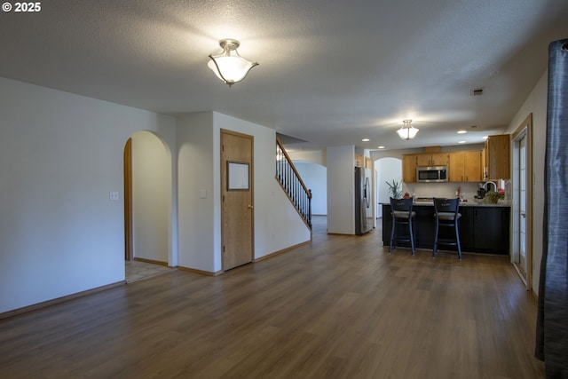 14604 NW 7th Pl, Vancouver, WA 98685 - kitchen with appliances with stainless steel finishes, arched walkways, dark wood finished floors, brown cabinets, and a kitchen bar