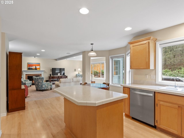 kitchen featuring a lit fireplace, dishwasher, tile countertops, and a sink