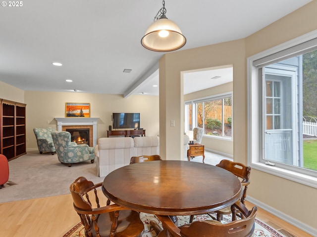 dining space with light wood finished floors, visible vents, baseboards, a glass covered fireplace, and recessed lighting