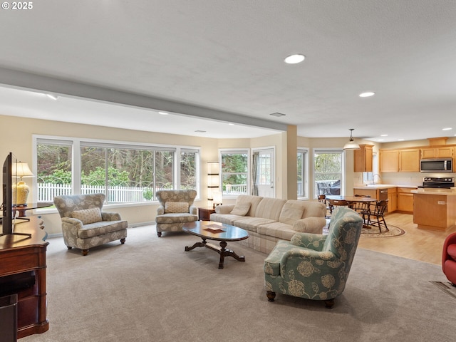 living area featuring recessed lighting, light colored carpet, and a healthy amount of sunlight