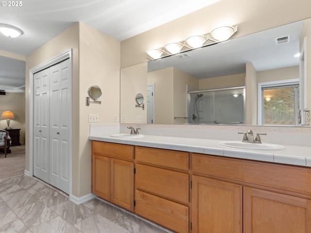 full bathroom featuring double vanity, a stall shower, a sink, and visible vents