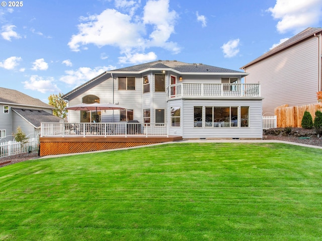 rear view of property featuring a yard, a wooden deck, and fence