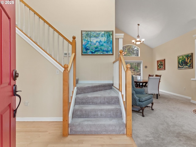 entrance foyer with an inviting chandelier, wood finished floors, high vaulted ceiling, baseboards, and stairs