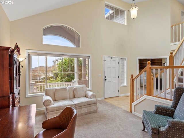 carpeted living room featuring high vaulted ceiling, baseboards, and stairs