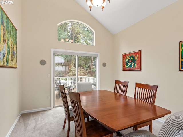 dining area with high vaulted ceiling, light carpet, a notable chandelier, and baseboards