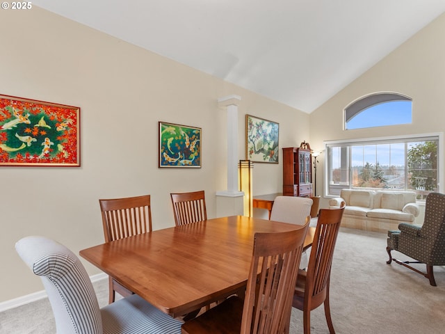 dining room with light carpet, high vaulted ceiling, and ornate columns