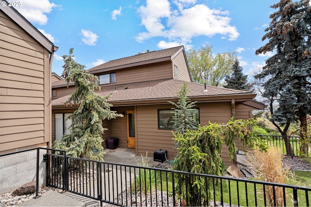 view of front of property with a patio, a shingled roof, and fence