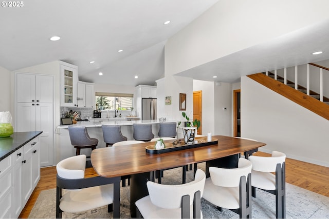 dining room featuring recessed lighting, high vaulted ceiling, light wood-type flooring, and stairs