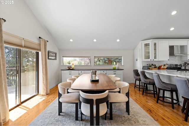 dining area with light wood-style floors, plenty of natural light, and lofted ceiling