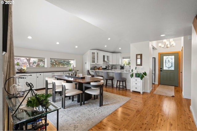 dining area with recessed lighting, an inviting chandelier, vaulted ceiling, and light wood-type flooring