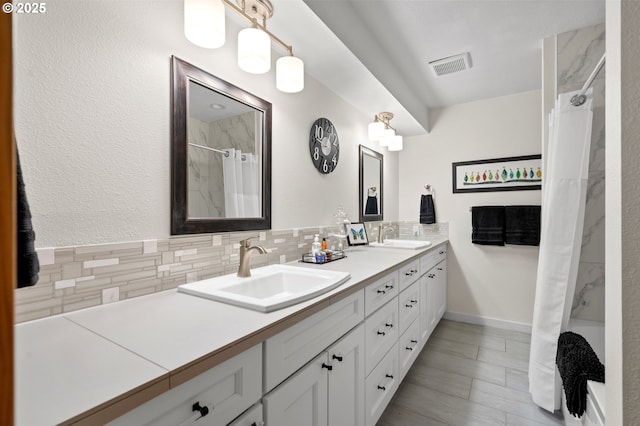 full bathroom with a sink, a shower with curtain, tasteful backsplash, and visible vents