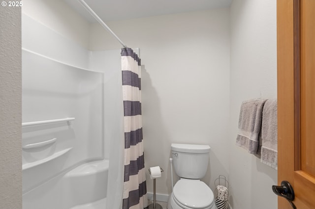 bathroom with baseboards, curtained shower, and toilet