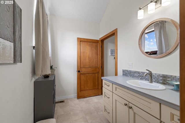 bathroom with baseboards, visible vents, decorative backsplash, and vanity