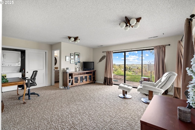 living area with a textured ceiling, stacked washer / drying machine, visible vents, and light carpet