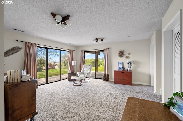 sitting room with carpet, a textured ceiling, and visible vents