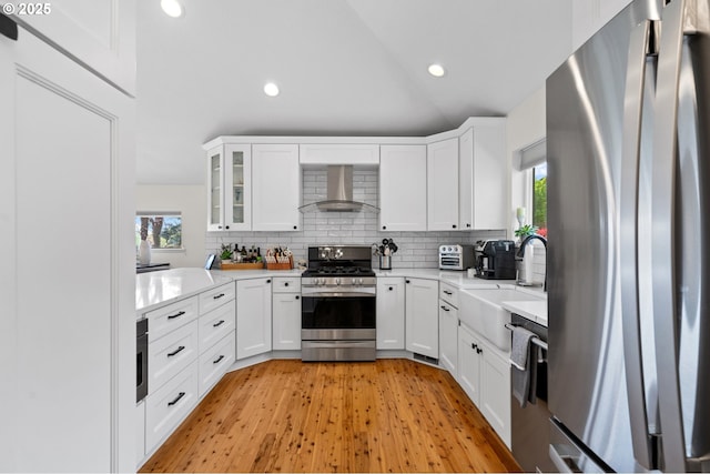 kitchen with a sink, light countertops, wall chimney exhaust hood, stainless steel appliances, and tasteful backsplash
