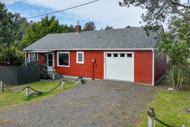 ranch-style home with a garage, a chimney, roof with shingles, gravel driveway, and fence