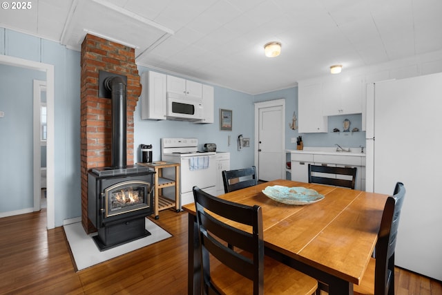 dining space with a wood stove and wood finished floors