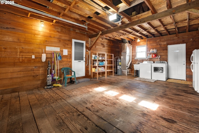 garage featuring washing machine and dryer, freestanding refrigerator, and wooden walls