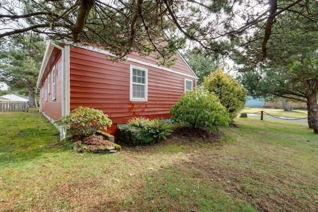 view of side of property featuring a lawn and fence