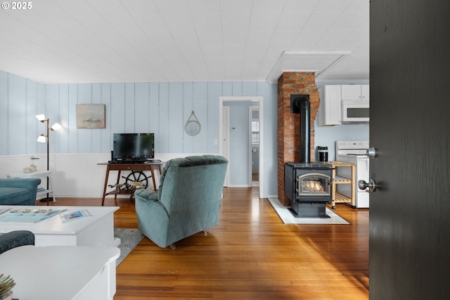 living area with wood finished floors and a wood stove